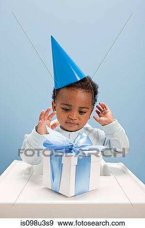 Stock Photo - Baby boy sitting in highchair with gift box. Fotosearch