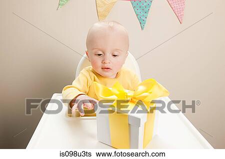 Baby boy sitting in highchair with gift box View Large Photo Image Stock Photograph - Baby boy sitting in highchair with gift box. Fotosearch