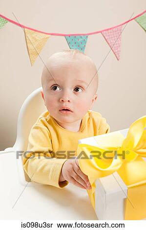 Stock Photography - Baby boy sitting in highchair with gift box. Fotosearch