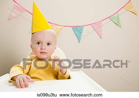 Stock Photograph - Baby boy sitting in highchair with bunting. Fotosearch