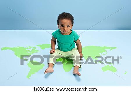 Stock Image - Baby boy sitting on world map on floor. Fotosearch