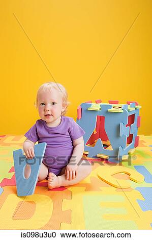 Stock Image - Baby girl playing with toy alphabet letters. Fotosearch
