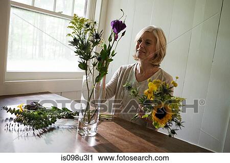 Mature woman arranging flowers View Large Photo Image Stock Image - Mature woman arranging flowers. Fotosearch