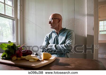 Stock Photo - Senior man preparing food indoors. Fotosearch