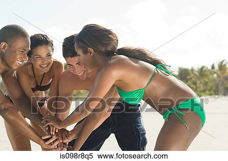 Stock Photography - Friends on beach with hands together. Fotosearch