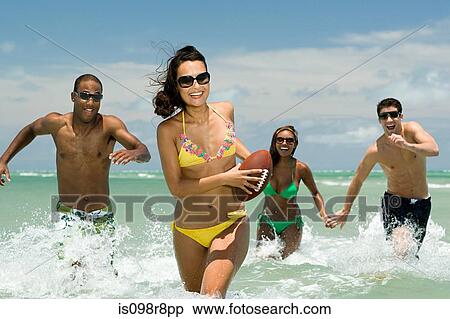 Friends running in sea with football View Large Photo Image Stock Photography - Friends running in sea with football. Fotosearch