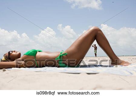 Woman sunbathing and man in distance View Large Photo Image Stock Image - Woman sunbathing and man in distance. Fotosearch