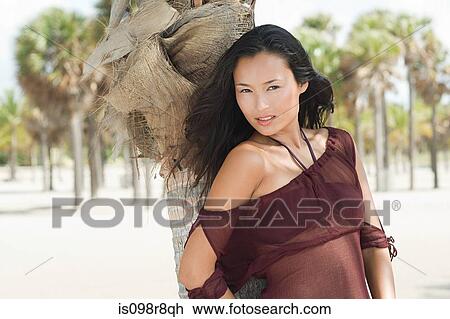 Stock Image - Young woman by palm tree. Fotosearch