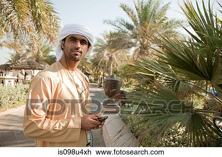 Stock Image - Middle Eastern man listening to music on mobile phone. Fotosearch