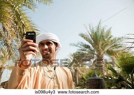 Stock Image - Middle Eastern man listening to music on mobile phone. Fotosearch