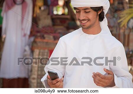 Middle Eastern man looking at mobile phone View Large Photo Image Stock Photo - Middle Eastern man looking at mobile phone. Fotosearch