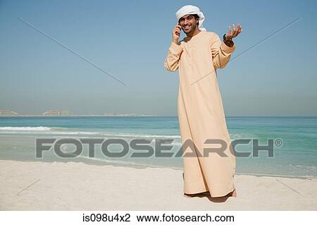 Middle Eastern man using mobile phone on the beach View Large Photo Image Stock Image - Middle Eastern man using mobile phone on the beach. Fotosearch