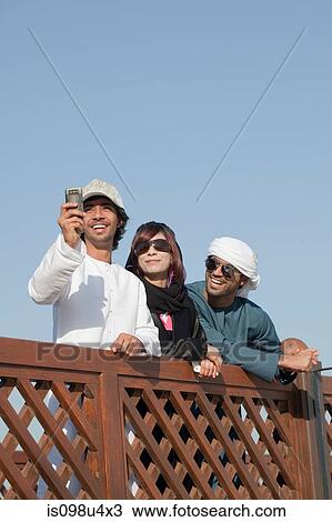 Stock Image - Middle Eastern people by fence, low angle view. Fotosearch