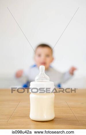 Baby bottle in foreground and baby in background View Large Photo Image Stock Image - Baby bottle in foreground and baby in background. Fotosearch