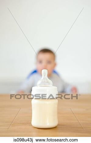 Stock Image - Baby bottle in foreground and baby in background. Fotosearch