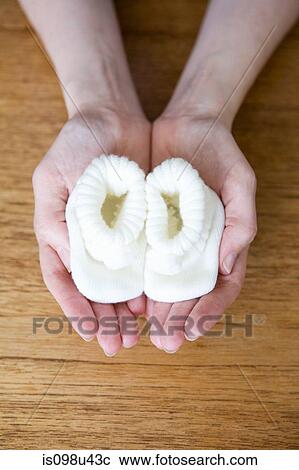 Stock Image - Pregnant woman holding baby booties. Fotosearch