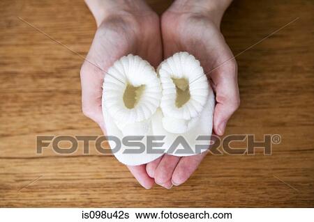 Pregnant woman holding baby booties View Large Photo Image Stock Photograph - Pregnant woman holding baby booties. Fotosearch