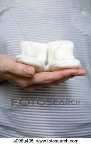 Pregnant woman holding baby booties View Large Photo Image Stock Photography - Pregnant woman holding baby booties. Fotosearch