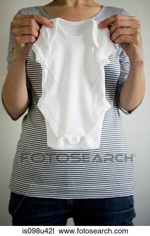 Pregnant woman holding babygro View Large Photo Image Stock Image - Pregnant woman holding babygro. Fotosearch