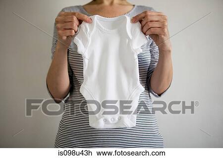 Pregnant woman holding babygro View Large Photo Image Stock Image - Pregnant woman holding babygro. Fotosearch