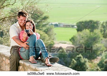 Young couple photographing themselves View Large Photo Image Stock Photograph - Young couple photographing themselves. Fotosearch