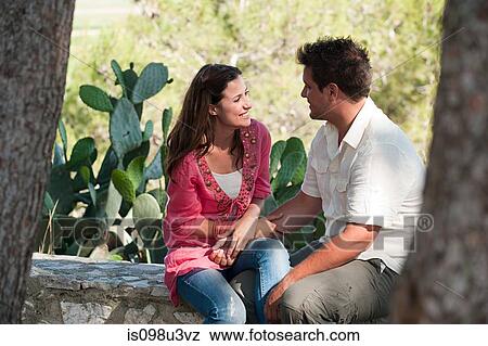 Stock Photo - Young couple sitting on stone wall. Fotosearch