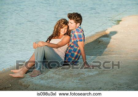 Young couple sitting near lake View Large Photo Image Stock Image - Young couple sitting near lake. Fotosearch
