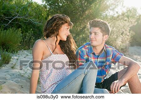 Young couple sitting on sand View Large Photo Image Stock Image - Young couple sitting on sand. Fotosearch