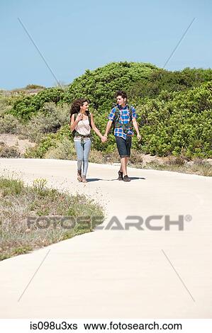 Young couple walking down rural road View Large Photo Image Stock Photograph - Young couple walking down rural road. Fotosearch