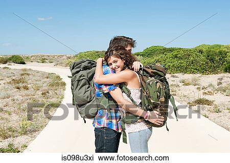 Young couple wearing backpacks embracing View Large Photo Image Stock Image - Young couple wearing backpacks embracing. Fotosearch