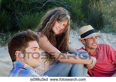 Young friends sitting on sand View Large Photo Image Stock Image - Young friends sitting on sand. Fotosearch