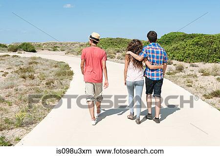 Young friends walking down rural road, rear view View Large Photo Image Picture - Young friends walking down rural road, rear view. Fotosearch