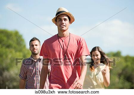 Stock Image - Young friends walking down rural road. Fotosearch