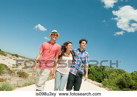 Young friends walking down rural road View Large Photo Image Stock Photo - Young friends walking down rural road. Fotosearch