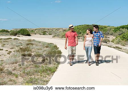 Stock Photograph - Young friends walking down rural road. Fotosearch
