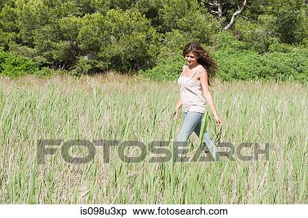 Young woman walking through field View Large Photo Image Stock Photography - Young woman walking through field. Fotosearch
