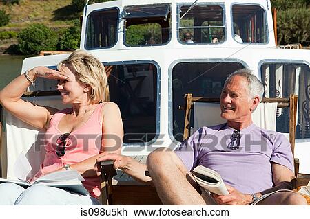 Stock Image - Senior couple sitting on deckchairs on a boat. Fotosearch