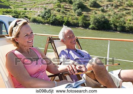 Stock Photograph - Senior couple sitting on deckchairs on a boat. Fotosearch