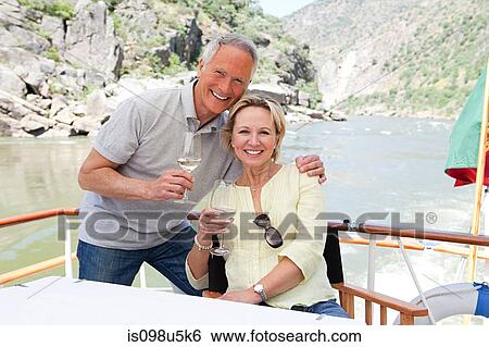 Stock Photograph - Senior couple with glasses of wine on a boat holiday. Fotosearch