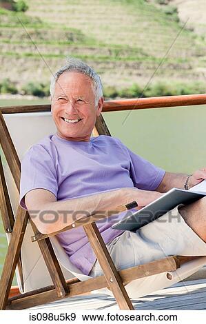 Senior man reading book on a boat holiday View Large Photo Image Stock Photo - Senior man reading book on a boat holiday. Fotosearch
