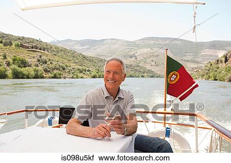 Stock Image - Senior man with a glass of wine on a boat holiday. Fotosearch