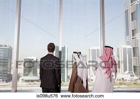 Businessmen looking through window in dubai office View Large Photo Image Stock Photograph - Businessmen looking through window in dubai office. Fotosearch