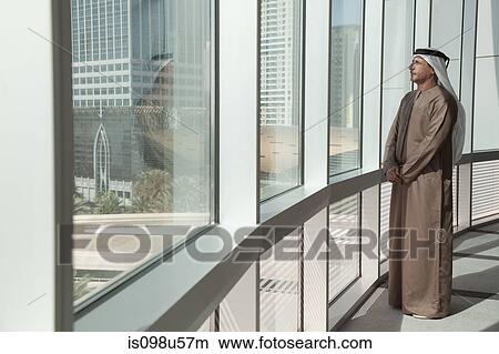 Middle eastern businessman looking out of office window View Large Photo Image Picture - Middle eastern businessman looking out of office window. Fotosearch
