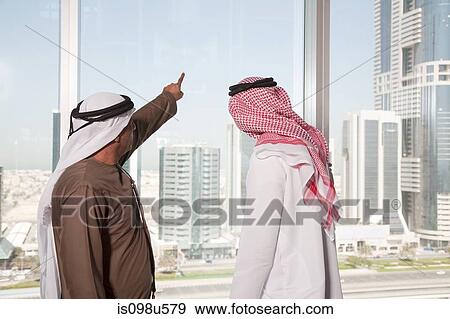 Middle eastern businessmen looking at dubai through office window View Large Photo Image Stock Photo - Middle eastern businessmen looking at dubai through office window. Fotosearch