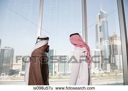 Middle eastern businessmen looking at dubai through office window View Large Photo Image Stock Photograph - Middle eastern businessmen looking at dubai through office window. Fotosearch
