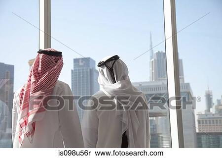 Middle eastern businessmen looking at dubai through office window View Large Photo Image Stock Photography - Middle eastern businessmen looking at dubai through office window. Fotosearch