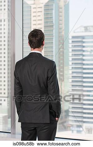 Rear view of businessman looking out of office window View Large Photo Image Stock Image - Rear view of businessman looking out of office window. Fotosearch