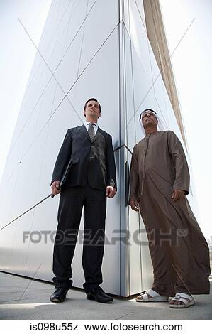 Stock Photo - Western and middle eastern businessmen outside modern building. Fotosearch