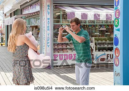 Teenage boy taking picture of girlfriend with teddy bear View Large Photo Image Picture - Teenage boy taking picture of girlfriend with teddy bear. Fotosearch