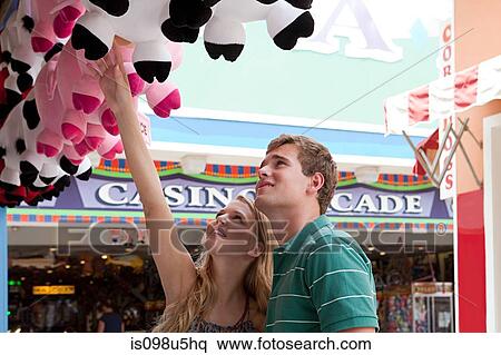 Stock Photography - Teenage couple looking at teddy bears at fun fair. Fotosearch